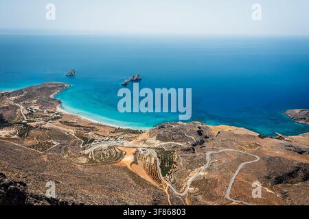 Luftpanoramablick auf die Küste in der Nähe von Xerokambos im Südosten Kretas, Griechenland, mit türkisblauem Wasser, schroffen Hügeln, kurvenreichen Straßen und abgelegenem M Stockfoto