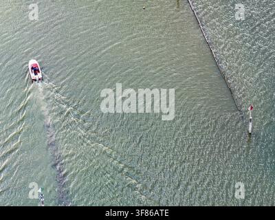 Motorboot fährt in den Hafen von Moss ein. Wellen bilden sich auf der Wasseroberfläche. Der Wasserstand im Bodensee liegt aufgrund des heißen Sommers auf einem niedrigen Niveau Stockfoto