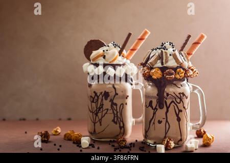 Schokoladenmilchshake mit Eis und Schlagsahne, Marshmallow, süßem Popcorn, Keksen, Waffeln, serviert in einem Glasmason-Glas. Stockfoto