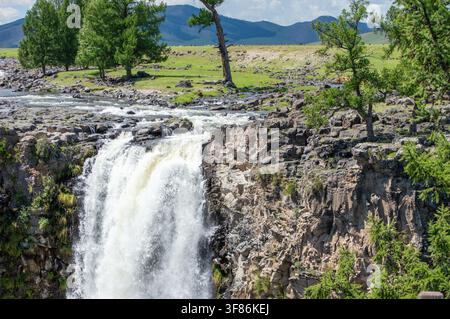 Orchon-Tal, Mongolei – 4. August 2026: Touristen am Fluss über dem Orchon-Wasserfall (Ulaan Tsutgalan), mit grasenden Pferden auf der Steppe. Stockfoto