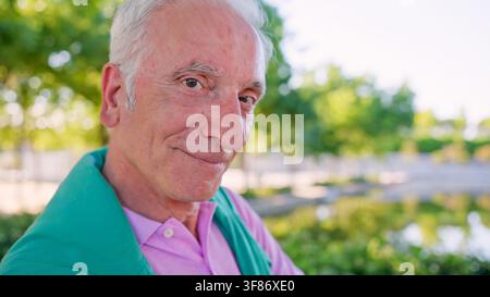 Senior Mann lächelt im Park im Freien und genießt den Ruhestand Stockfoto