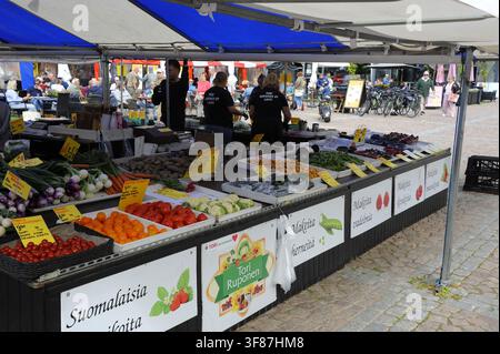 Ein lebhafter lokaler Marktstand in Lahti, Finnland, gefüllt mit frischem Gemüse, Beeren und regionalen Produkten unter einem blau-weißen Zelt. Stockfoto