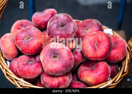 Frische reife Donut-Pfirsiche in einem Weidenkorb. Hochwertiges Foto Stockfoto
