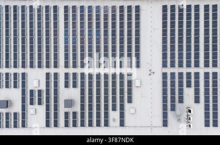 Luftbild von oben über eine ausgedehnte Solarpanel-Anlage, die ein großes Industrielagerhausdach bedeckt, kommerzielle erneuerbare Energien und Nachhaltigkeit Stockfoto