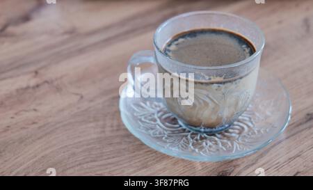 Gläserbecher mit heißem schwarzem Kaffee und Milch auf Holzoberfläche Stockfoto
