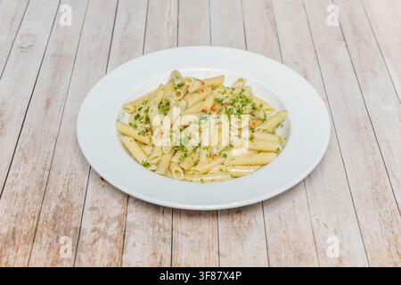 Penne-Pasta Aglio e Olio mit Chiliflocken und frischer Petersilie auf weißem Teller geworfen Stockfoto