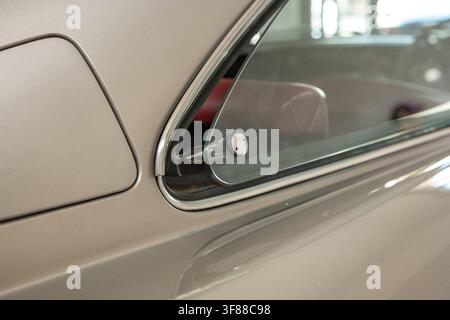 Seitenansicht, Nahaufnahme des ausfahrbaren Heckscheiben-Glases und der Chromverzierungen an einer klassischen Vintage-Autokarosserie in Silberbeige. Stockfoto
