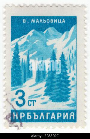 BULGARIEN — 26. Oktober 1964: 3 Stotinki grünlich-blauer Briefmarkenwert zeigt den schneebedeckten Malyovitsa-Gipfel in den Rila-Bergen. Vor einem kühlen Himmelshintergrund zeigt das alpine Wintermotiv immergrüne Tannen in tiefem Schnee im Vordergrund, die zu schroffen, schneebedeckten Berggipfeln in der Ferne aufsteigen. Dieses Grafikdesign ist Teil einer Serie zur Förderung des bulgarischen Tourismus, der natürlichen Wahrzeichen, der malerischen Ausblicke und spiegelt den staatlich geförderten Inlands Tourismus, das ökologische Erbe, den Wintersport und die Wertschätzung der ikonischen Balkanlandschaften in der Volksrepublik Bulgarien wider Stockfoto