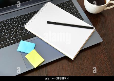 Arbeitsplatz mit Laptop, Notizbuch, Stift und Kaffee von oben Stockfoto