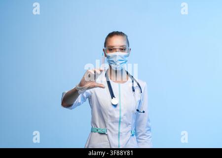 Medizinischer Mitarbeiter in Schutzausrüstung hält eine Spritze, symbolisch für Impfung, Gesundheitsversorgung und medizinische Behandlung Stockfoto