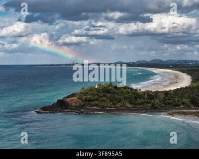 Luftbild des Fingal Head Leuchtturms auf der felsigen Landzunge mit einem Regenbogen über der Küstenlinie und einem Sandstrand in Fingal Head, New South Wales, Australien Stockfoto