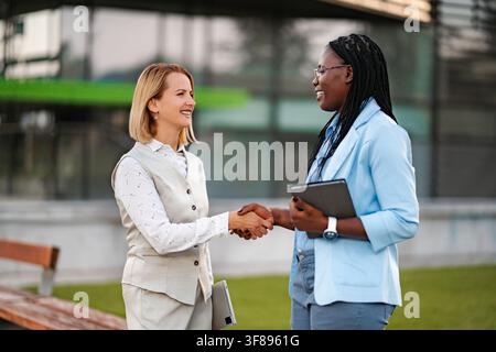 Geschäftsfrauen, die sich nach einem erfolgreichen Partnerschaftstreffen im Freien die Hand schütteln Stockfoto