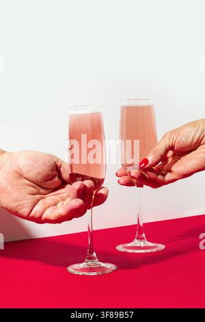 Mann und Frau Hände nehmen ein Glas Rosenschaum auf Rot und weiß. Festtagskonzept. Hochzeit oder Hochzeitstag. Valentinstag. Stockfoto