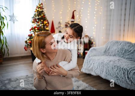 Mutter und Tochter teilen eine freudige Umarmung während der Weihnachtsferien zu Hause Stockfoto