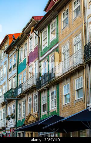 Lebendige, farbenfrohe Gebäude säumen eine bezaubernde Straße in Braga, Portugal. Jede Fassade bietet einzigartige Pastelltöne, verwitterte Texturen und verzierte Balkone Stockfoto