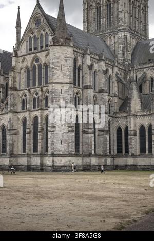 Blick auf die historische Salisbury Cathedral mit ihrer kunstvollen gotischen Steinarchitektur, spitzen Bögen und hohen Türmen, auf der Menschen herumlaufen Stockfoto
