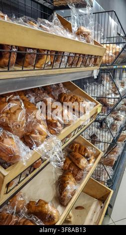 Verpacktes Brot und Gebäck, arrangiert auf Holz- und Drahtregalen, schafft eine einladende Präsentation von frischen Backwaren in einer Supermarkt-Bäckereiabteil Stockfoto