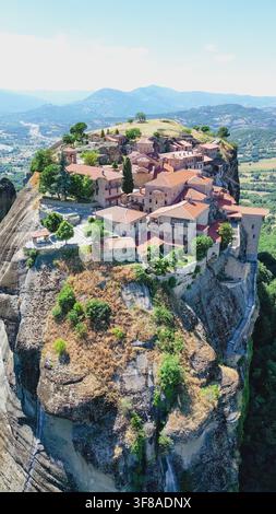 Vertikale Drohnen-Luftaufnahme des Heiligen Dreifaltigkeitsklosters, das auf einem dramatischen Klippenfelsen unter blauem Himmel im Wahrzeichen von Meteora nahe Kalambaka Thessalien steht Stockfoto