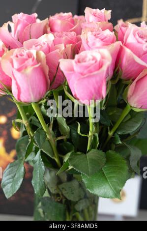 romantischer Strauß aus rosa Rosen, arrangiert in einer Glasvase auf einem unscharfen Indoor-Hintergrund, Nahaufnahme von oben, elegant und detailliert floral Stockfoto