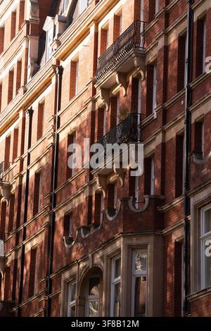 Sonnenlicht beleuchtet die kunstvolle rote Backstein-Viktorianische Architektur entlang der Kensington High Street und hebt ein Wahrzeichen des Londoner Erbes hervor. Stockfoto