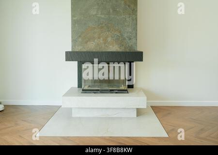 Eleganter moderner Kamin mit Natursteinverkleidung, der bis zur Decke reicht, in einem minimalistischen Wohnzimmer. Großer visueller Vorteil für Hausheizsysteme Stockfoto
