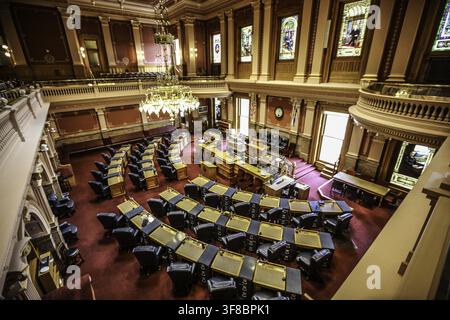 Ansicht des prächtigen Parlamentssaals im Colorado State Capitol mit Reihen von Holztischen, rotem Teppichboden und einem großen Kronleuchter in Denver, C Stockfoto