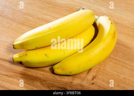 Drei reife Bananen liegen auf einer Holzoberfläche Stockfoto