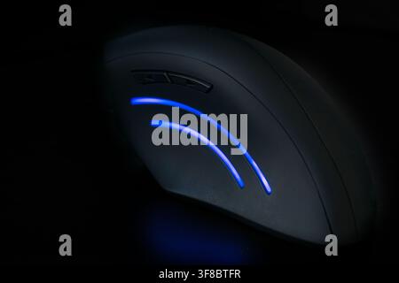Dunkle ergonomische Computermaus mit leuchtender blauer Akzentbeleuchtung für Gaming Stockfoto
