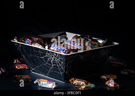 Grand Rapids, MI, USA - 31. Oktober 2025: Halloween-Süßigkeiten in einer schwarzen Schale mit Spinnweben, schwarzer Hintergrund Stockfoto