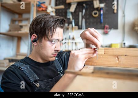 Konzentrierter professioneller Mann, Restaurator, der Messungen an einem Flicken an einem alten Fensterrahmen am Tisch vornimmt Stockfoto