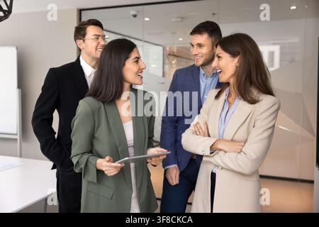 Multikulturelle Firmenangestellte lachen und haben Spaß während eines informellen Bürotreffens Stockfoto