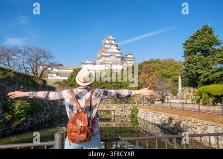 Asiatische Frau betrachtet Kirschblüten und das Schloss in Himeji, Japan. Stockfoto