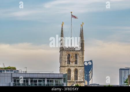 Ansicht des historischen Turms der Southwark Cathedral mit der St.-Georgs-Flagge, die vor einem blauen Himmel in London, England, Vereinigtes Königreich, weht. Stockfoto