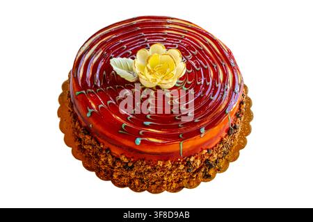 ein runder, geschichteter Karamellkuchen mit einem glänzenden spiegelglasierten Karamelloberteil, verziert mit einer eingespritzen weißen Schokoladenblüte, blaugrünen marmorierten Wirbeln und einem cr Stockfoto