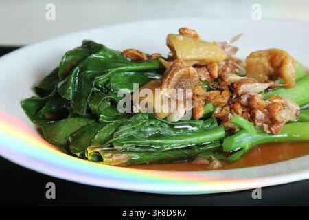 tir-gerösteter chinesischer Kohl mit knusprigem Schweinebauch auf einem weißen Teller, traditionelles thailändisches Essen und beliebtes lokales Gericht. Stockfoto