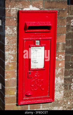 Rot lackierter Royal Mail Briefkasten. Georg VI., rechteckig und in eine Ziegelmauer eingebaut. Stockfoto