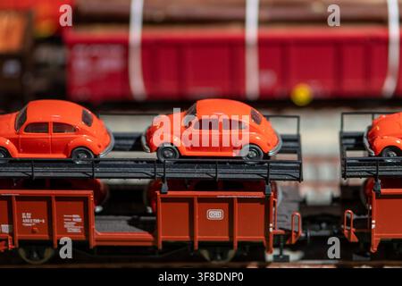 WIEN, ÖSTERREICH, 26. November 2022: Nahaufnahme von orangefarbenen Volkswagen Beetle Miniaturautos, die auf Modellgüterwagen mit sichtbarem DB-Logo transportiert werden. Stockfoto