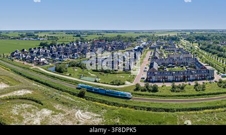 Luftaufnahme einer neuen Wohnsiedlung mit vorbeifahrendem Zug in Europa Stockfoto