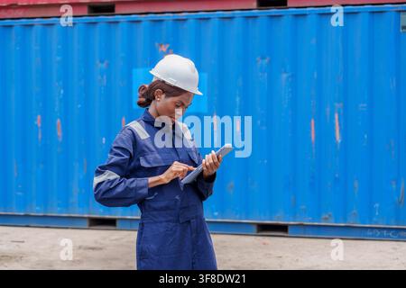 Schwarze Frau mit Schutzhelm, die Daten auf einem Tablet auf einer Baustelle überprüft, um Sicherheit und Effizienz sicherzustellen. Ideal für Bau, Ingenieurwesen und Arbeit Stockfoto