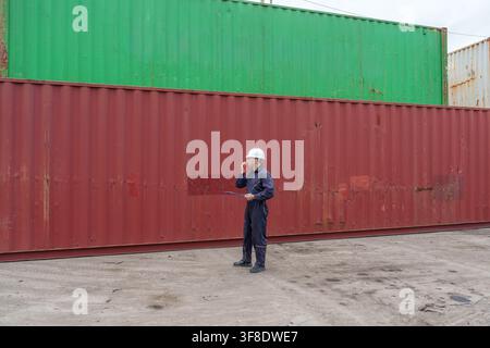 Bauarbeiter inspiziert Frachtcontainer in einem Versandhof für Logistikmanagement. Ideal für Industrie, Versand, Transport und Arbeit Stockfoto