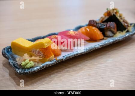 Verschiedenes japanisches Sushi auf einem Teller angeordnet, einschließlich Lachs, Thunfisch, Garnelen, Tamago, Ikura und anderen bunten Sushi-Sorten, serviert mit Wasabi und Stockfoto