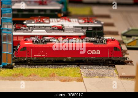 WIEN, ÖSTERREICH, 26. November 2022: Eine rote OBB-Modelllokomotive ist auf Gleisen innerhalb eines detaillierten Miniatur-Eisenbahndioramas ausgestellt. Stockfoto