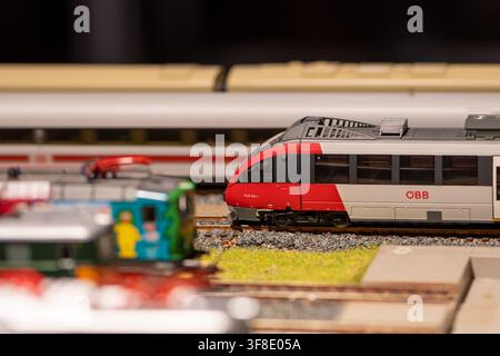 WIEN, ÖSTERREICH, 26. November 2022: Ein roter und grauer OBB-Modell-Personenzug steht auf Gleisen innerhalb eines Modelleisenbahnlayouts mit verschwommenen Zügen im Stockfoto