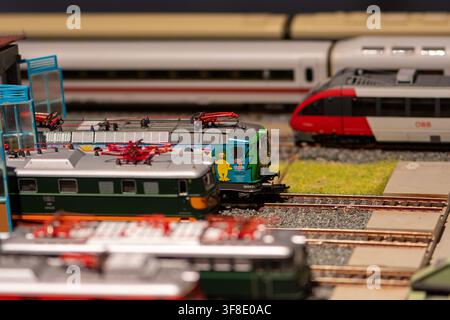WIEN, ÖSTERREICH, 26. November 2022: Mehrere Miniaturlokomotiven und Personenzüge stehen auf parallelen Gleisen in einer detaillierten Modelleisenbahnanlage Stockfoto