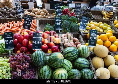 Bunte Auswahl an frischen Früchten und Gemüsen, die in Weidenkörben auf einem traditionellen Bauernmarktstand präsentiert werden. Wassermelonen, Trauben, Äpfel, Melonen Stockfoto