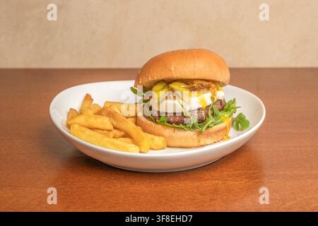 Gourmet-Burger mit Brie-Käse, Rucola und Gurken, serviert mit Steak-Pommes Stockfoto