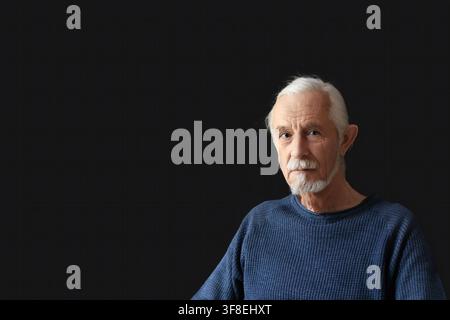 Niedrig belichtetes Studio-Porträt eines schönen alten Mannes mit grauen Haaren, der in die Kamera schaut. Horizontal. Stockfoto