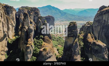 Luftbild der dramatischen Konglomerat-Fels Säulen im Tal von Meteora nahe der Stadt Kalabaka mit grünen Bäumen und fernen Bergen in den Ländereien von Thessalien, Griechenland Stockfoto