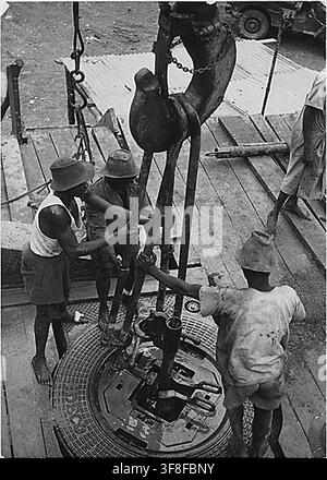 Einheimische Arbeiter in Gabun, Französisch-Äquatorialafrika, montieren Bohrrohre mit einem Drehtisch von Beaumont, Texas, der durch die Economic Cooperation Administration geliefert wurde, während sie für die Societe des Petroles d'Afrique Equatoriale Francaise arbeiten. Stockfoto