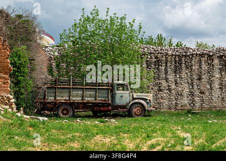 Verlassener rostiger Vintage-Truck neben einer alten Steinmauer in Griechenland Stockfoto